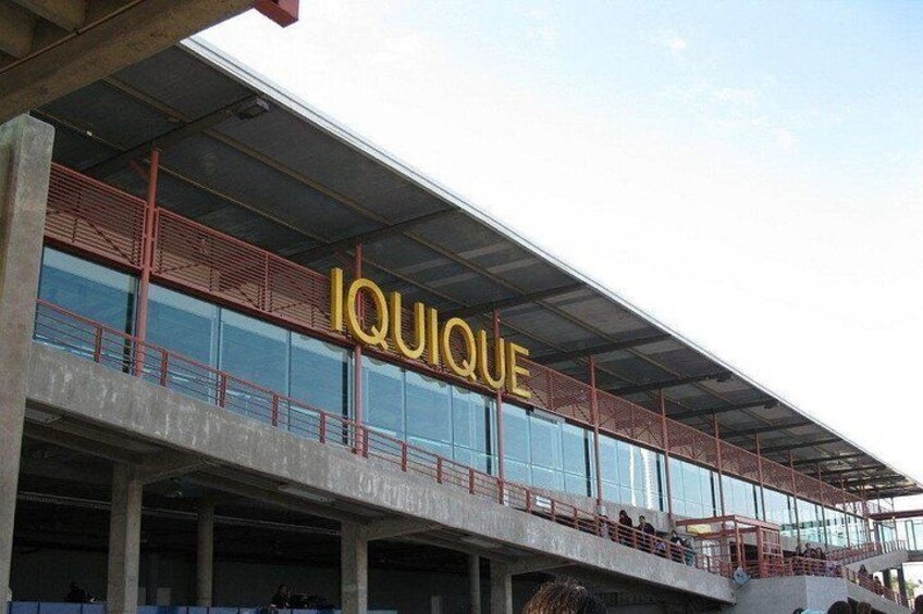 A modern building with a glass facade and the word 'IQUIQUE' prominently displayed. 3