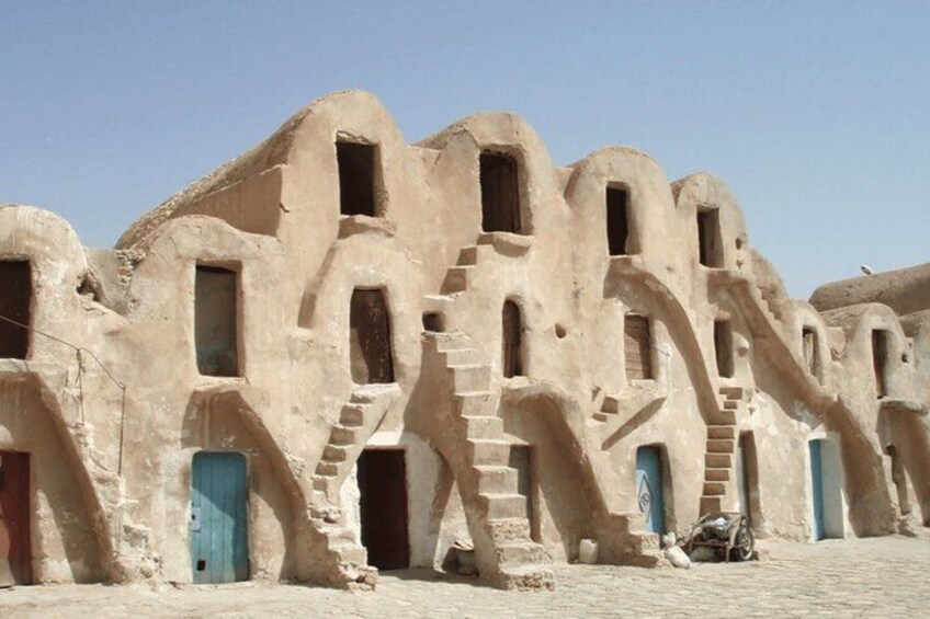 A row of traditional mud-brick buildings with arched doorways and windows. 2