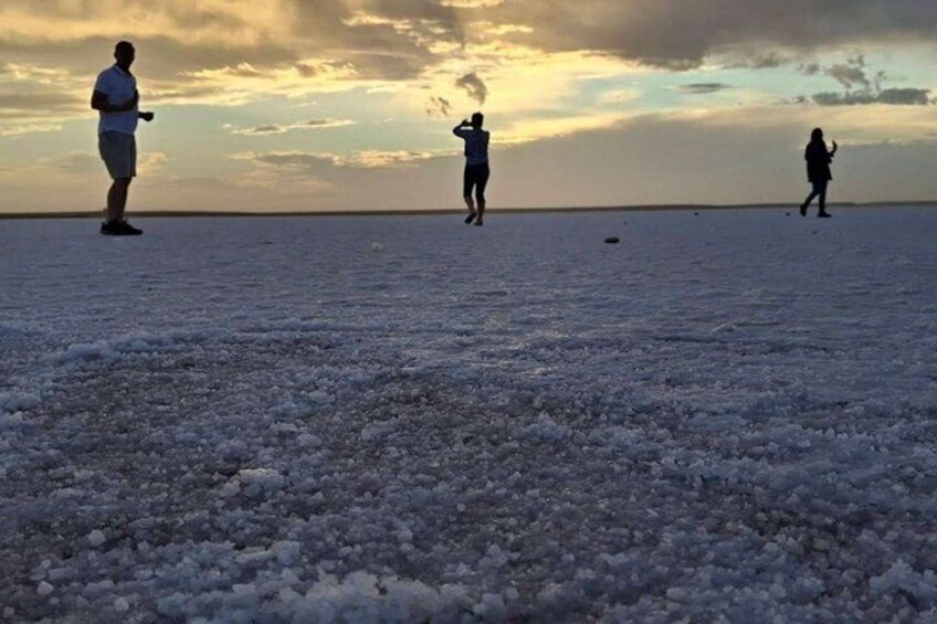 A flat, expansive salt flat with three people walking. 5