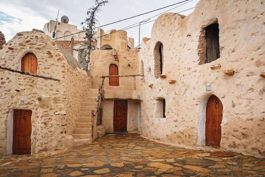 A narrow alley with traditional stone buildings, wooden doors, and a cobblestone path. 4