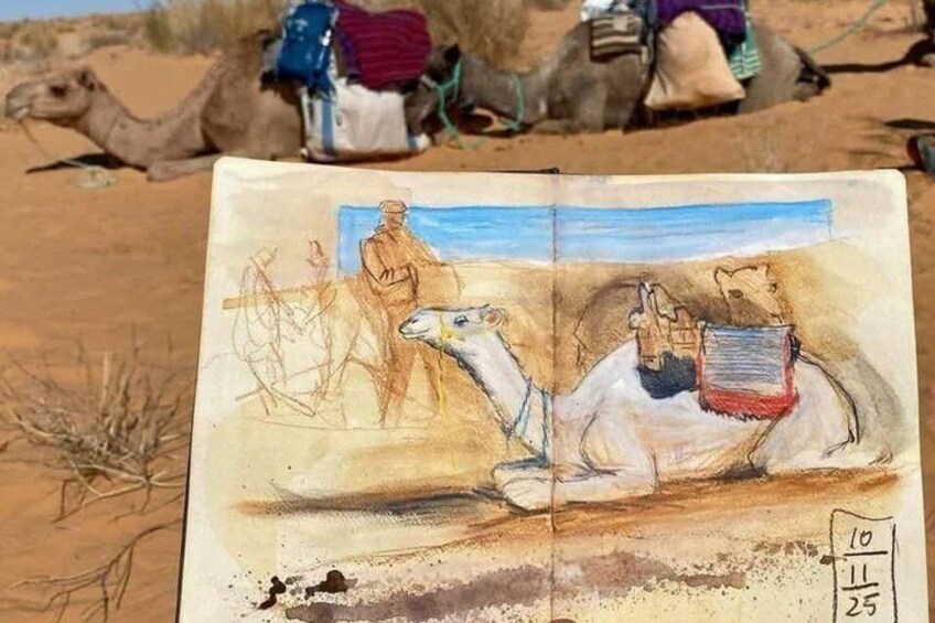 A sketchbook with a drawing of a camel and a person in a desert setting. 4