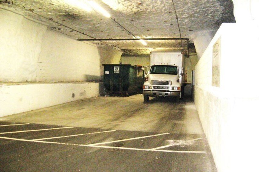 A parking garage with a white truck parked in a lane marked with arrows. 5