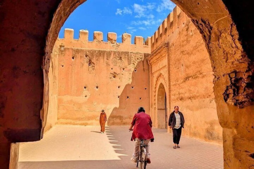 A historical fort with a central archway, a paved courtyard, and a clear blue sky. 1