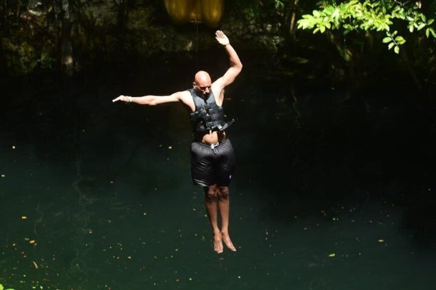 A person jumping into a body of water wearing a black wetsuit and life vest. 4