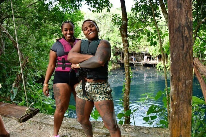 Two people standing by a water body surrounded by trees. 2