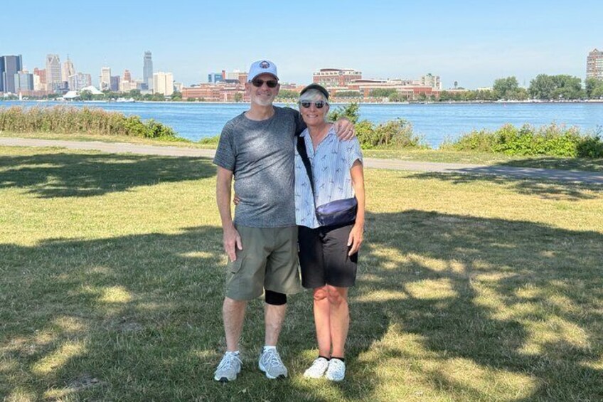 Two people standing on grass with a city skyline in the background. 1
