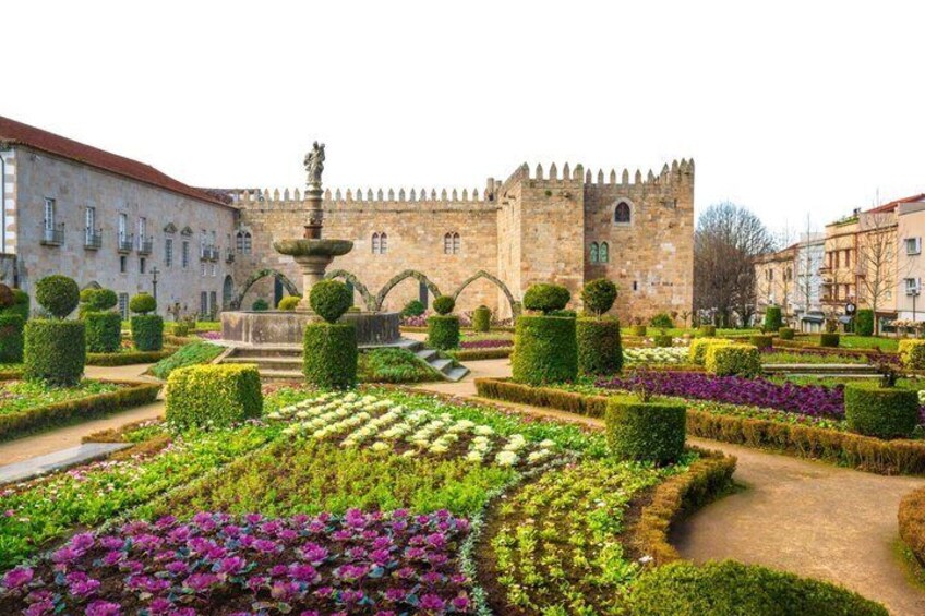 A historic castle with a moat, manicured gardens, and a fountain. 3