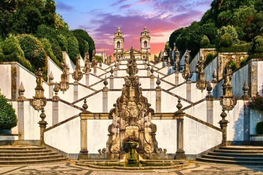 A grand staircase with ornate balustrades, a central fountain, and a bell tower in the background. 2