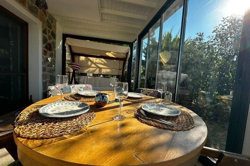 A round wooden table set for a meal with plates, glasses, and a centerpiece. 5