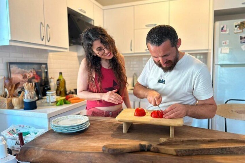 A kitchen with a cutting board, a knife, and a tomato. 1