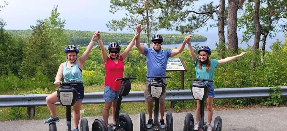 Four people on Segways, a scenic road, and a signpost. 1