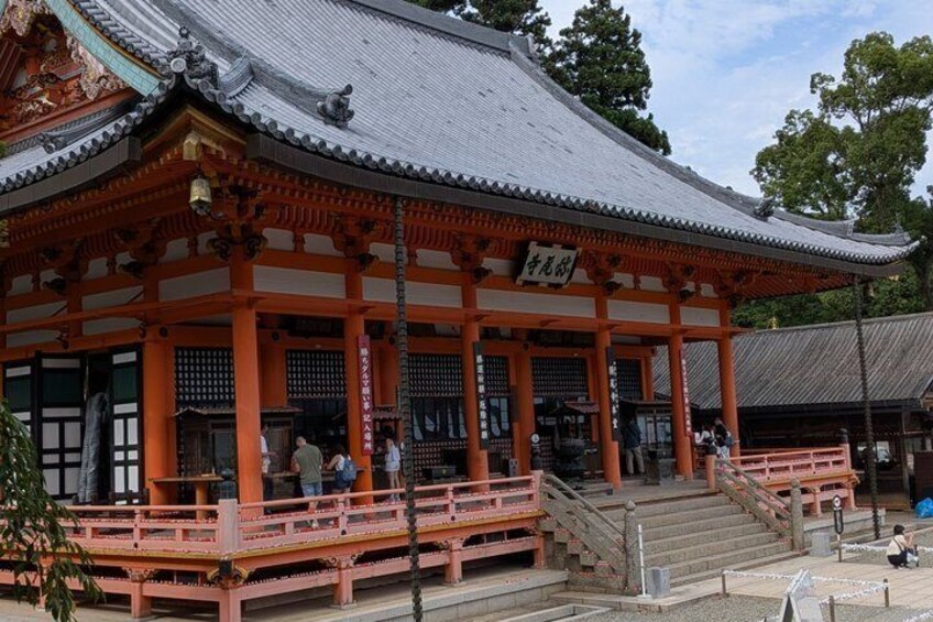 A traditional Japanese temple with a red torii gate, a stone staircase, and a signboard. 3