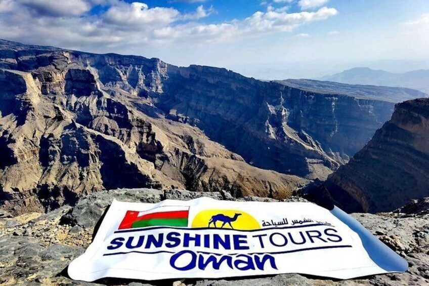 A mountainous landscape with a banner for Sunshine Tours Oman. 1