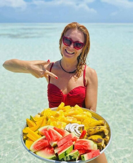 A person holding a tray of tropical fruits at a beach. 3