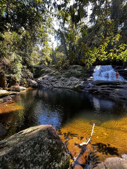 Un paysage naturel caractérisé par un plan d’eau aux eaux claires, des rochers et un feuillage dense. 2