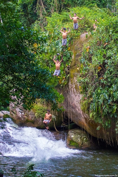 Una cascada con gente escalando y saltando desde un saliente rocoso. 4