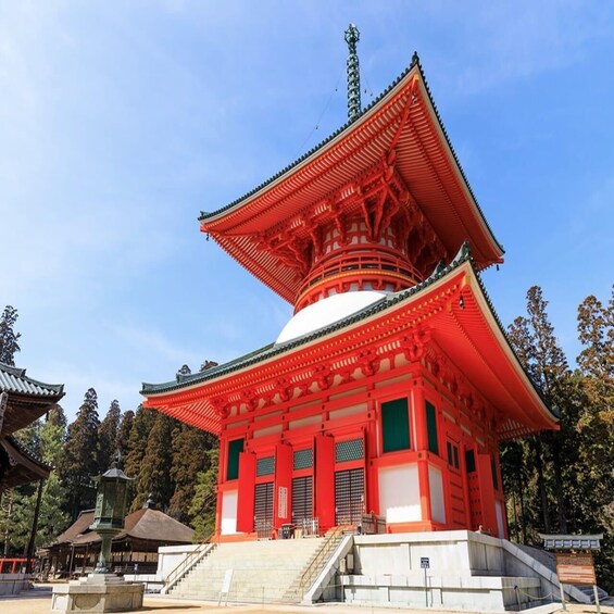 A traditional Japanese pagoda with a red and white color scheme, surrounded by trees and other pagodas. 1