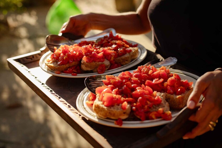 Two plates of bruschetta topped with diced tomatoes on a wooden tray. 3