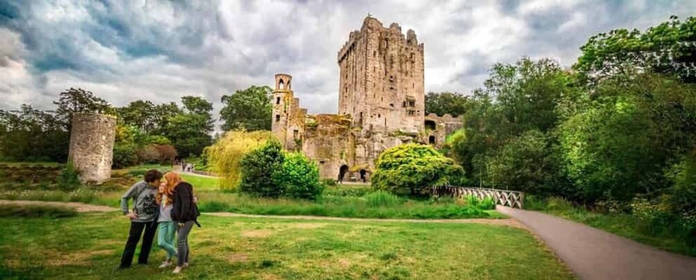 A historic castle surrounded by greenery, a pathway, and a stone tower. 3