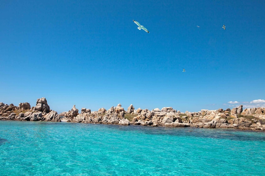 A coastal landscape with clear turquoise waters and rocky formations. 1