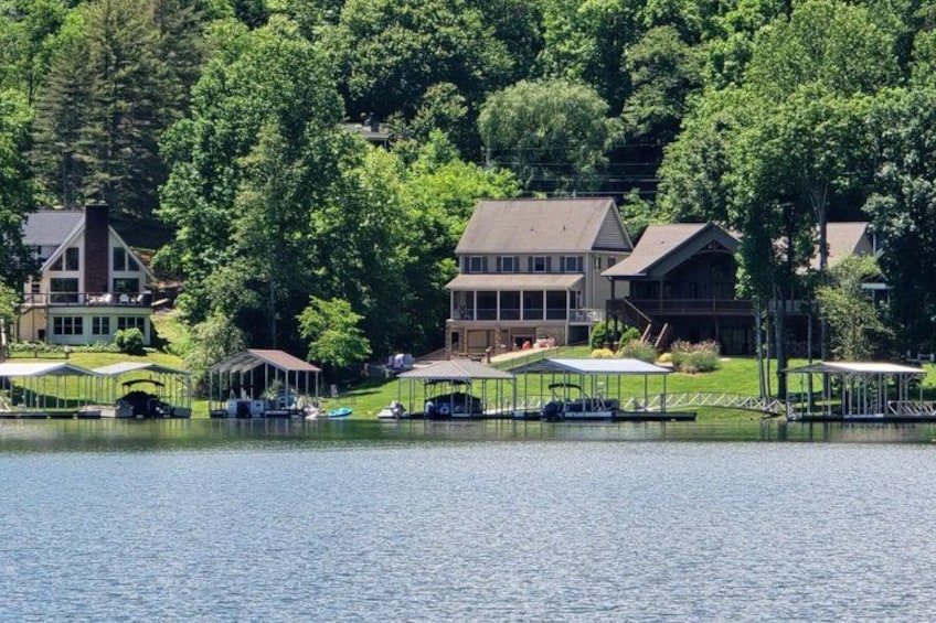 A lakeside property with multiple houses, docked boats, and covered areas. 3