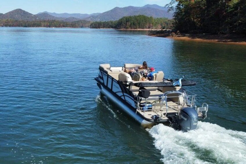 A motorboat with passengers on a calm lake surrounded by mountains. 2