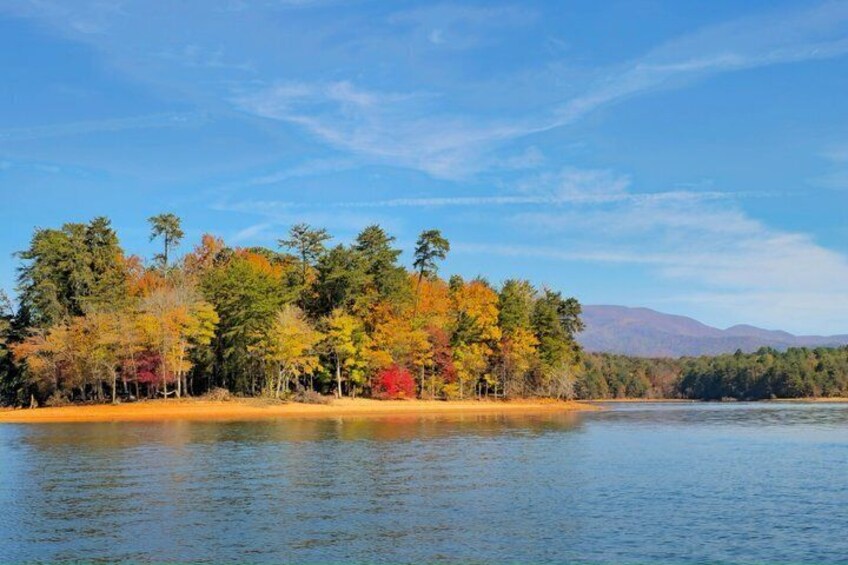 A lake surrounded by autumn-colored trees and distant mountains. 5
