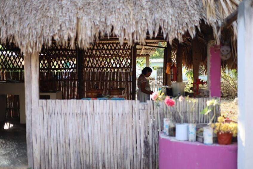 A thatched-roof structure with a person working inside, surrounded by wooden lattice and a pink wall. 5