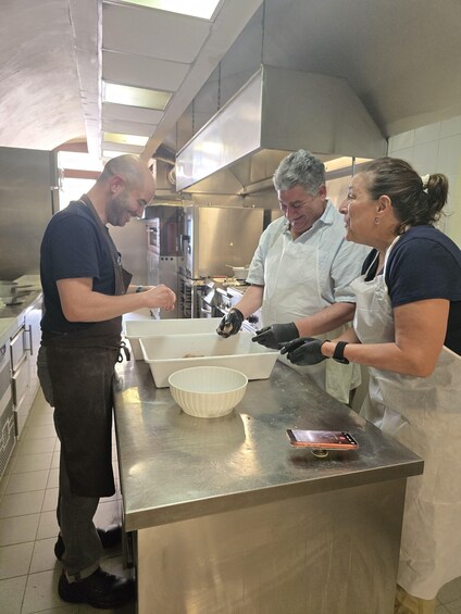 A kitchen with stainless steel countertops, a white bowl, and a person wearing a white apron. 1