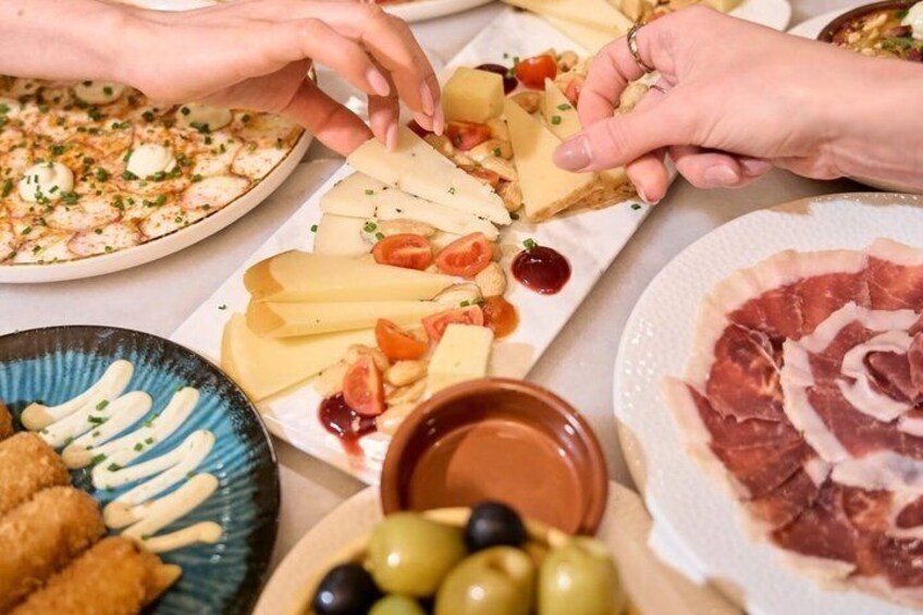 A variety of cheeses, meats, and olives on a table. 2