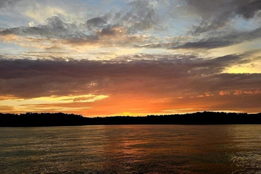 A sunset over a body of water with a silhouette of trees in the distance. 3