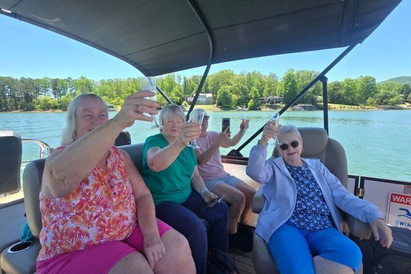 Four people on a boat with a lake and trees in the background. 3