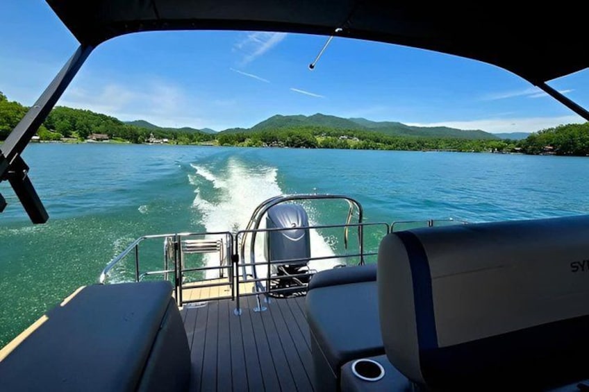 A boat on a calm lake with a wake behind it, surrounded by green hills. 4