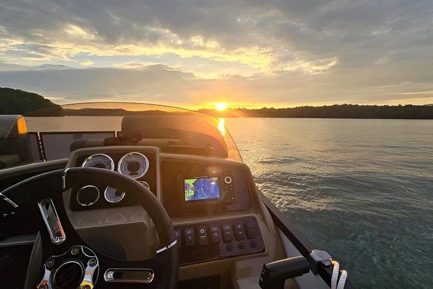 A boat's dashboard with a GPS screen, steering wheel, and control panel. 5