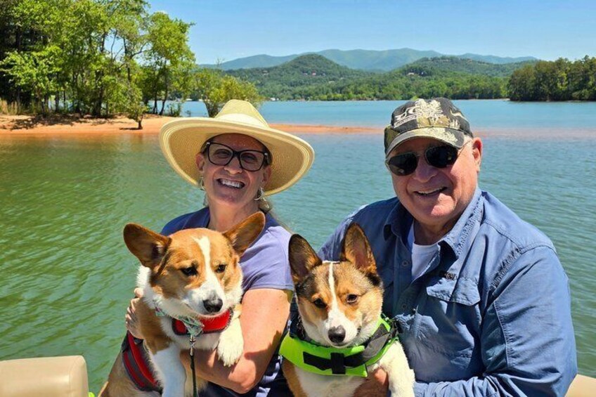 Two people on a boat with two dogs wearing life jackets. 2