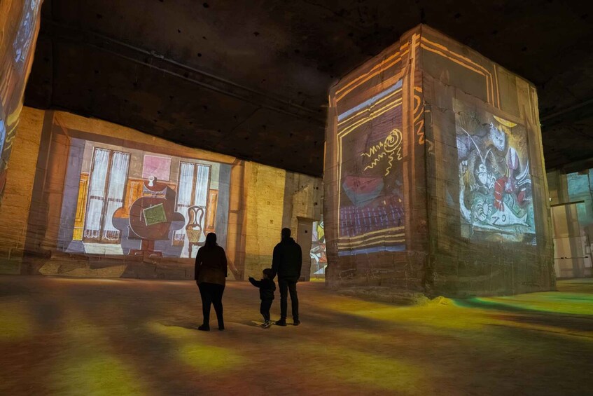 A projection of a large mural on a wall in an indoor space, with two people and a child observing it. 5