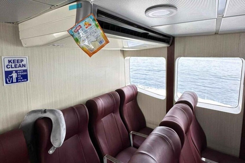 A cabin with maroon seats, a 'KEEP CLEAN' sign, and a window with a view of the sea. 4