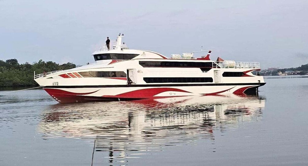 A large white and red speedboat on calm water with a cityscape in the background. 2