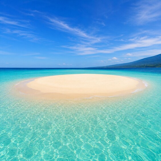 A clear turquoise sea, a sandy beach, and a mountain in the distance. 3