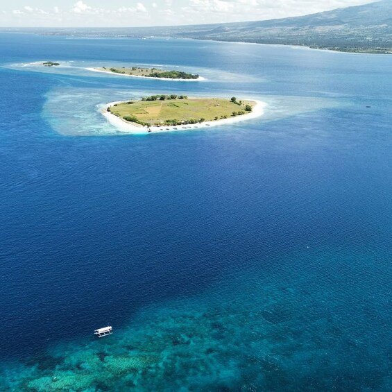 An aerial view of a large body of water with two islands, one with a white sandy beach and the other with green vegetation. 2