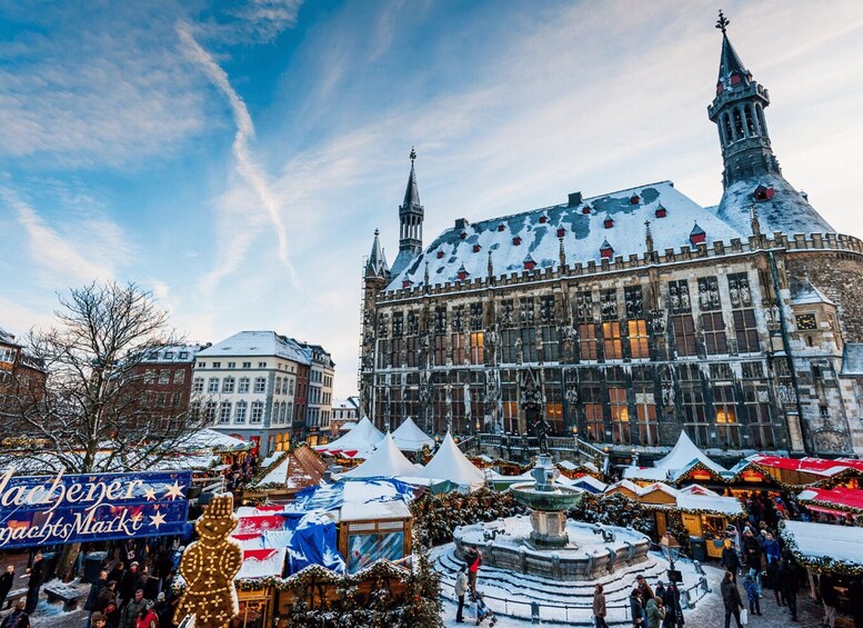 A historic building with a clock tower, surrounded by a festive market with tents and a snow-covered fountain. 4