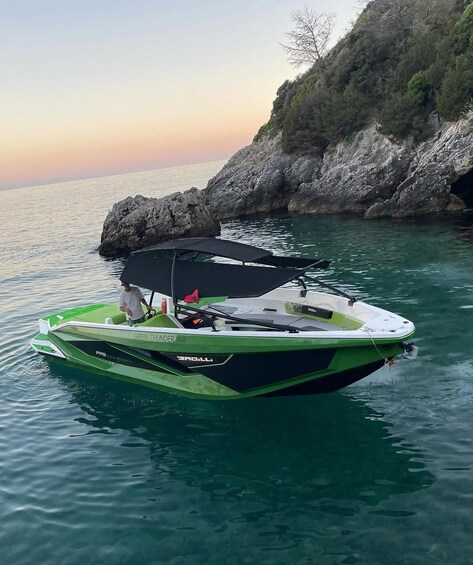 Ein grünes und weißes Schnellboot namens 'GREEN THUNDER' auf ruhigem Wasser in der Nähe von Felsen. 4