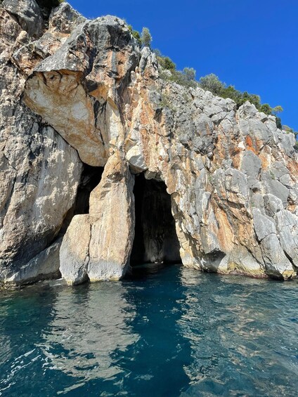 Eingang einer felsigen Küstenhöhle mit klarem, blauem Wasser. 3