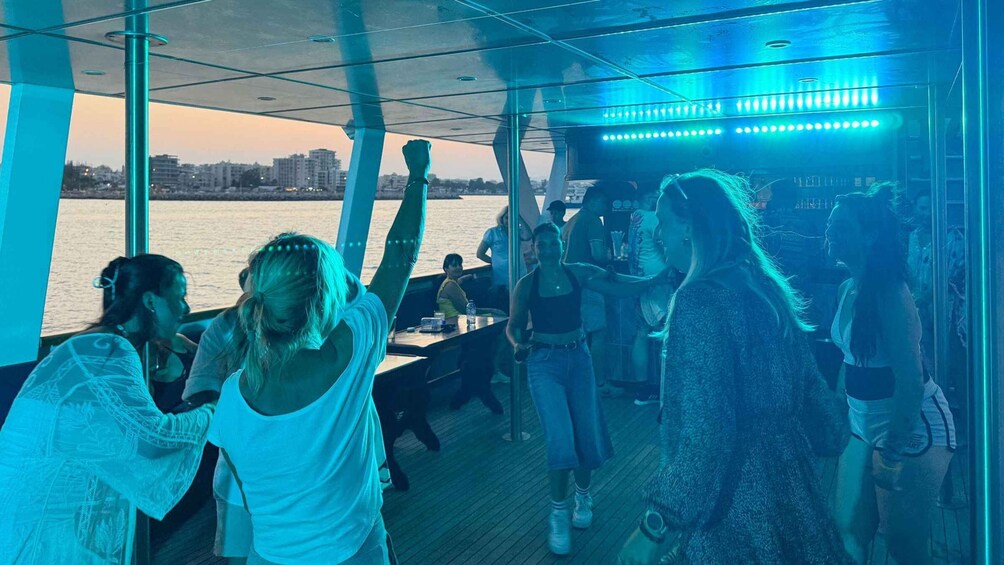 A group of people on a boat with a river and city skyline in the background. 3