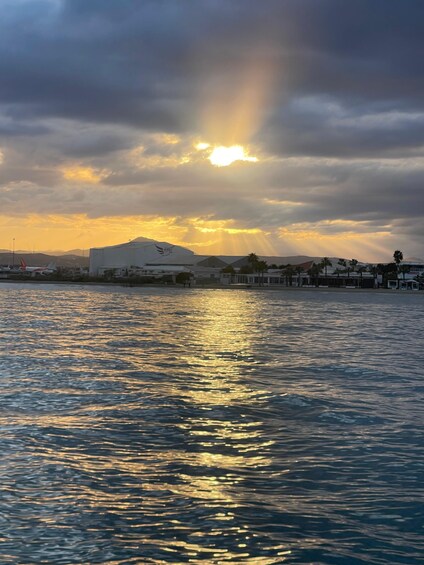 A sunset over a body of water with buildings and palm trees in the background. 2