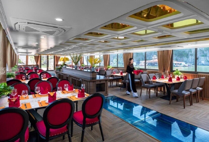 A restaurant with red chairs and tables, a pool, and a view of the water outside. 3