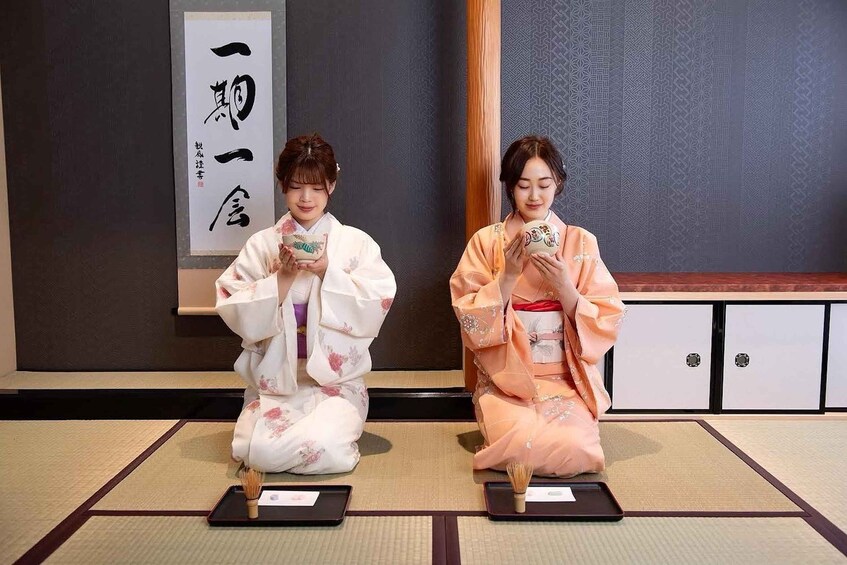 Two individuals in traditional Japanese attire seated on tatami mats with tea ceremony utensils. 3
