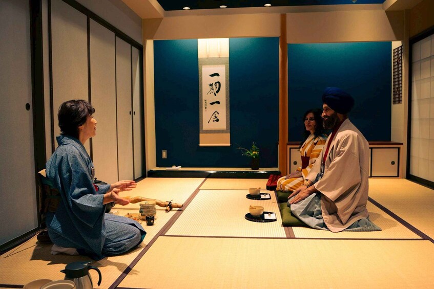 A traditional Japanese room with tatami flooring, a shoji screen, and a hanging scroll with Japanese characters. 2
