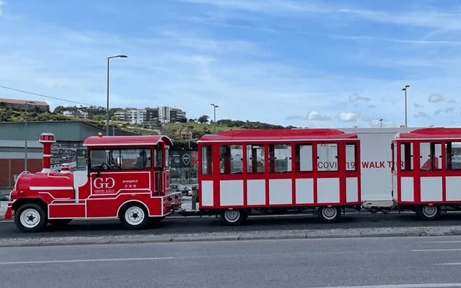 A red and white tram with 'COVID-19 WALK TOUR' written on it. 3