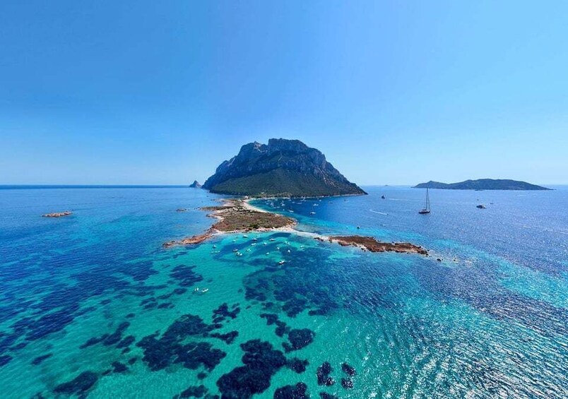 A clear blue sea with a rocky island in the center and a smaller island to the right. 4